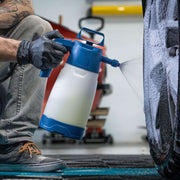 Homem utilizando o pulverizador IK FOAM Pro 2 ALK para aplicar espuma em um pneu durante a limpeza.