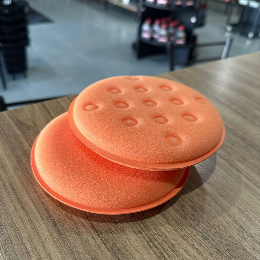 Aplicador de Espuma Kers Super Pro em cores laranja, ideal para aplicação de ceras e polidores, em superfície de madeira.